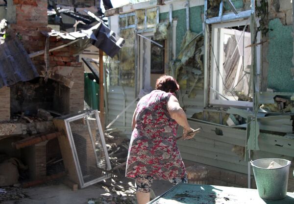 Женщина убирает мусор во дворе жилого дома в Донецке, пострадавшего в результате обстрела - Sputnik Абхазия