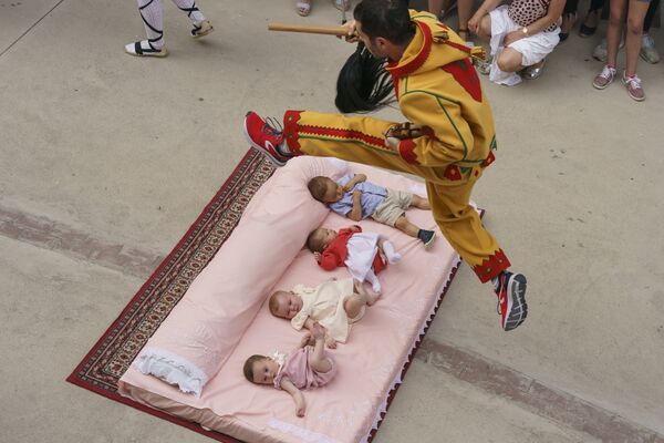 Мужчина, одетый в костюм дьявола, перепрыгивает через младенцев во время ежегодного фестиваля Эль Колачо в испанском городе Кастильо де Мурсия - Sputnik Абхазия