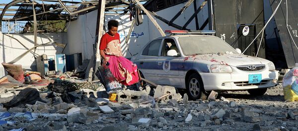 Мигрант собирает целую одежду после авианалета на лагерь беженцев в Ливии. 3 июля 2019  - Sputnik Абхазия