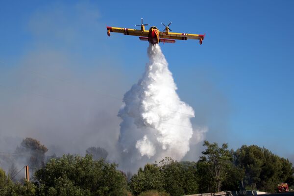 Противопожарный самолет сбрасывает воду на область пожара, возникшего в промышленной зоне у города Витроль во Франции - Sputnik Абхазия