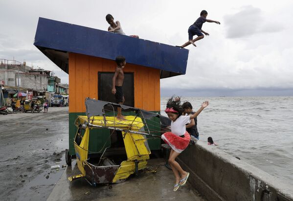 Дети прыгают в воду в бухте Манилы на Филиппинах после сильного ливня - Sputnik Абхазия