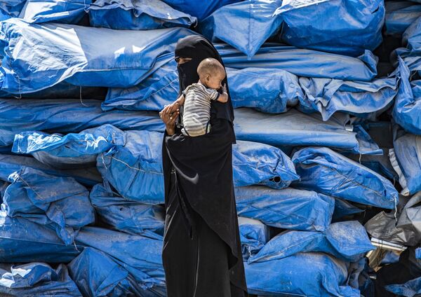 Женщина с никабе с ребенком на руках в лагере для перемещенных лиц al-Hol на северо-востоке Сирии - Sputnik Абхазия