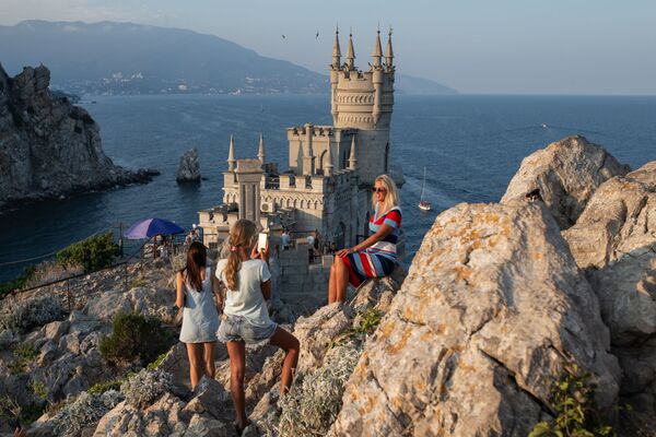 Отдыхающие фотографируются возле замка Ласточкино гнездо на береговой скале в поселке Гаспра в Крыму - Sputnik Абхазия