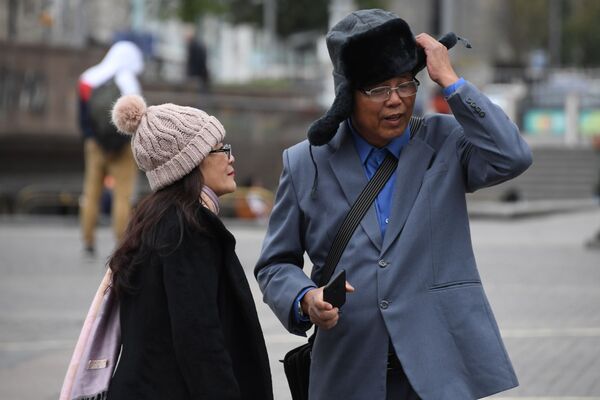 Иностранные туристы одевают теплые головные уборы на Манежной площади во время холодной погоды в Москве - Sputnik Абхазия