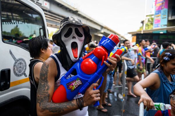 Человек в маске и с водяным пистолетом во время празднования буддийского нового года в Бангкоке - Sputnik Абхазия