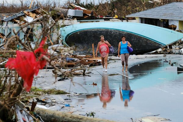 Женщины идут по завалам после урагана Дориан на острове Грейт-Абако в Марш-Харборе, Багамские острова - Sputnik Абхазия