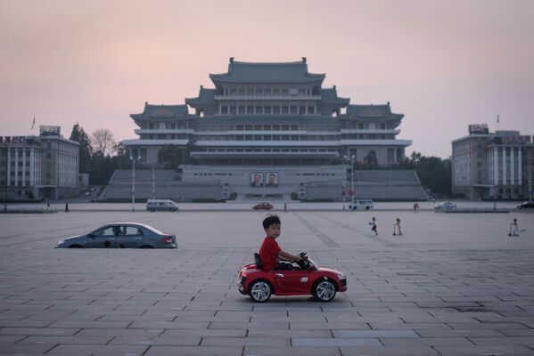 Мальчик на игрушечной машине на площади Ким Ир Сена в Пхеньяне, Северная Корея - Sputnik Абхазия