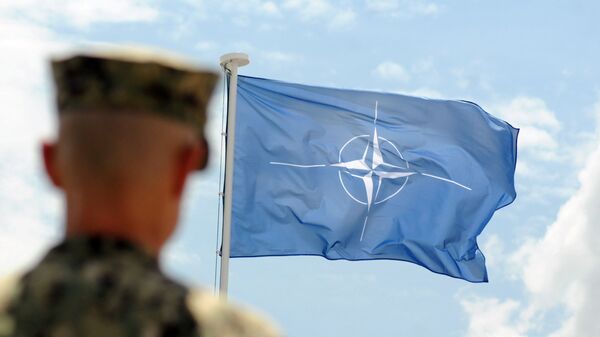 Военнослужащий НАТО на фоне флага НАТО в Косово - Sputnik Абхазия