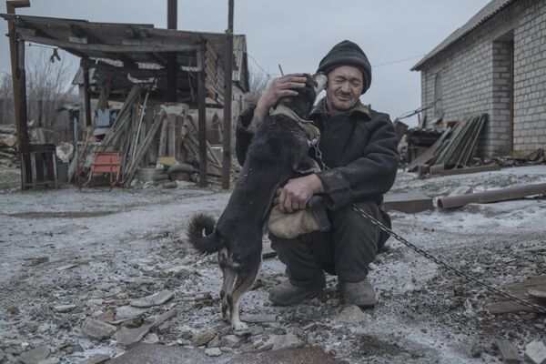 62-летний Александр Васильев со своей собакой - один из последних жителей поселка Новомарьевка Донецкой области, оказавшегося на линии соприкосновения противоборствующих сторон в Донбассе. Фотография из серии Серая зона, завоевавшей Гран-при фотоконкурса Intarget Photolux Award-2019. - Sputnik Абхазия