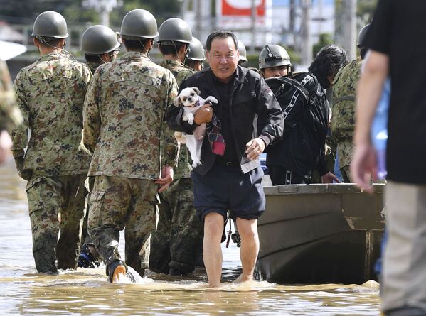Местный житель со своей собакой эвакуируется из зоны, затопленной рекой Абукума, префектура Фукусима, Япония - Sputnik Абхазия