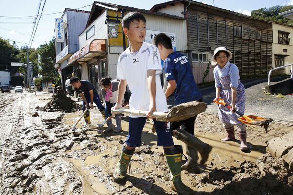 Школьники и жители города убирают грязь после наводнения, вызванного тайфуном Хагибис в Марумори, префектура Мияги, Япония - Sputnik Абхазия