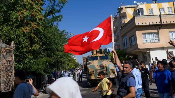 Мужчина развевает турецкий флаг, когда турецкие войска едут на автомашинах в направлении Тал-Абьяда в Сирии - Sputnik Абхазия