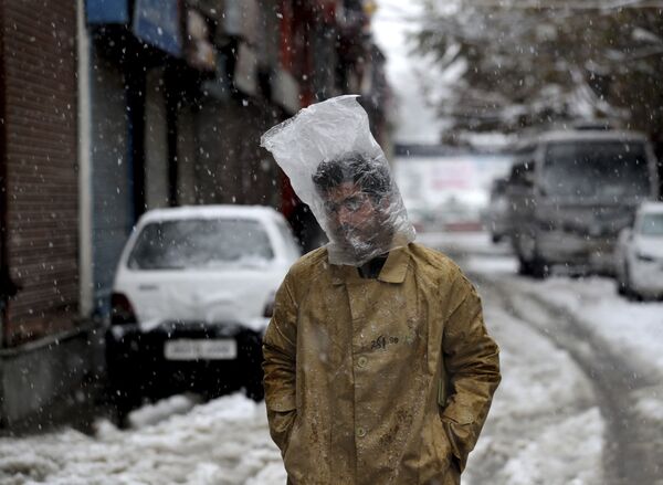 Мужчина прикрывает голову полиэтиленовым пакетом во время снегопада в Сринагаре, Кашмир - Sputnik Абхазия
