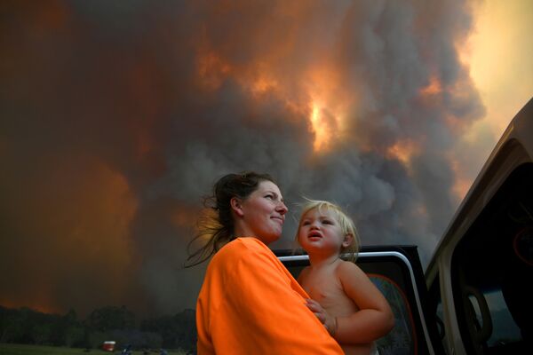 Женщина в ребенком на руках в дыму природных пожаров в Австралии - Sputnik Абхазия