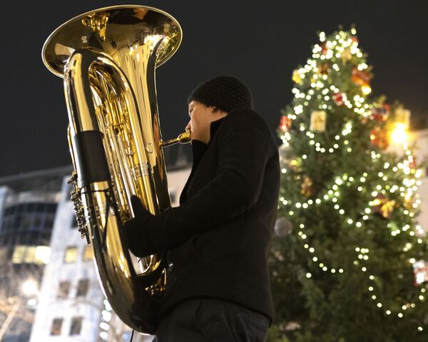Музыкант духового оркестра Rudersdorf Music Society играет на трубе на рождественском базаре в Вене - Sputnik Абхазия