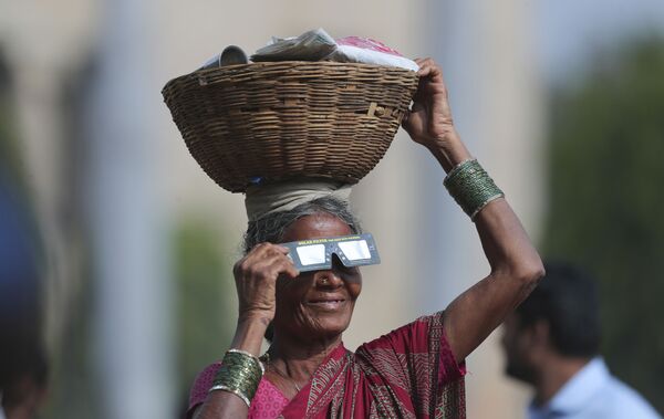Уличная торговка в Индии наблюдает солнечное затмение через специальные очки - Sputnik Абхазия