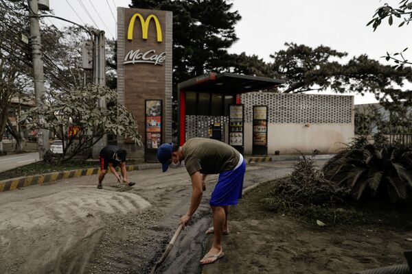 Рабочие убирают вулканический пепел рядом с закусочной McDonald's в городе Тагайтай, Филиппины - Sputnik Абхазия