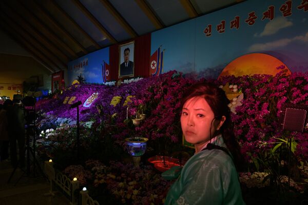 Посетительница под портретом Ким Ир Сена на цветочной выставке в рамках празднования Дня солнца в Пхеньяне.  - Sputnik Абхазия