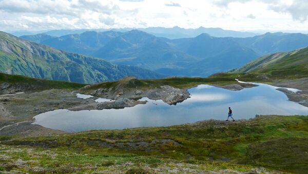 Путешественник проходит мимо горного водоема на Аляске - Sputnik Абхазия