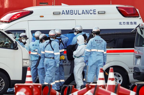 Пожарные в защитных костюмах помещают в машину скорой помощи заболевших пассажиров круизного лайнера Diamond Princes, помещенного в карантин у японского порта Йокогама - Sputnik Абхазия