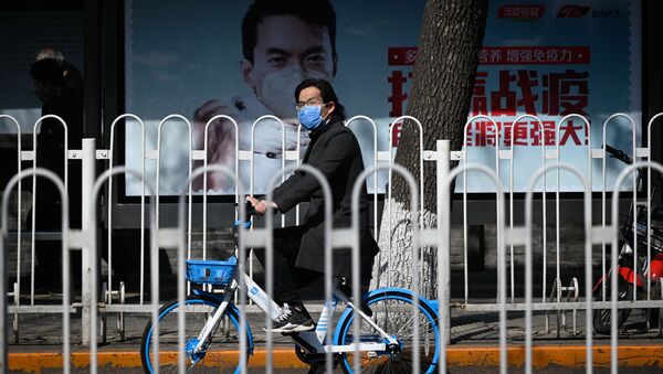 Человек, носящий маску, едет на велосипеде по улице в Пекине 11 марта 2020 года. - 11 марта Китай сообщил об увеличении числа случаев завоза коронавируса, что усиливает опасения, что инфекции из-за рубежа могут подорвать прогресс в прекращении распространения вируса - Sputnik Абхазия