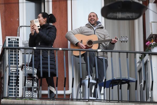 Мужчина с гитарой и женщина со смартфоном на одном из балконов в Милане - Sputnik Абхазия