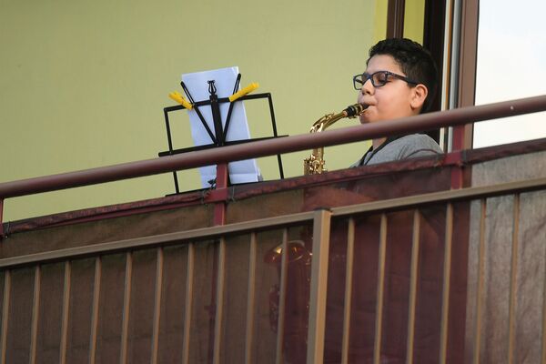 Мальчик играет на саксофоне на балконе своего дома во время карантина в Милане - Sputnik Абхазия