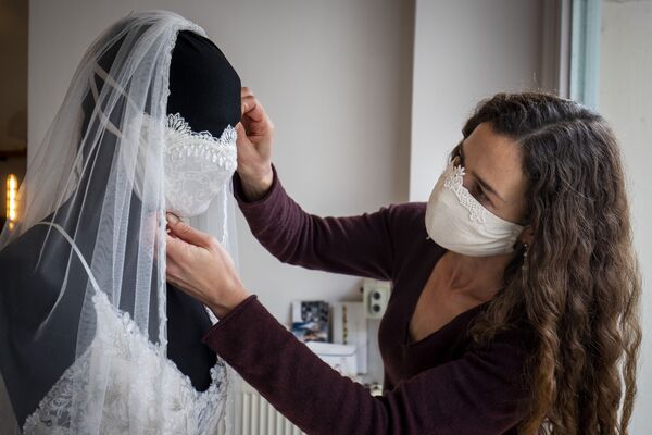 В Берлине дизайнер оформляет витрину магазина свадебных платьев, надевая на манекен специальную свадебную маску. - Sputnik Абхазия