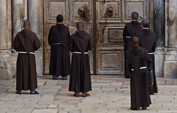  Францисканские монахи во время молитвы перед закрытой дверью Храма Гроба Господня - Sputnik Абхазия