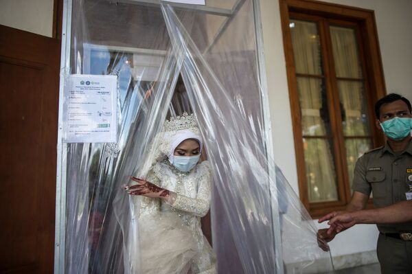 Индонезийская невеста в маске после дезинфекции во время свадебной церемонии в городе Сурабая - Sputnik Абхазия