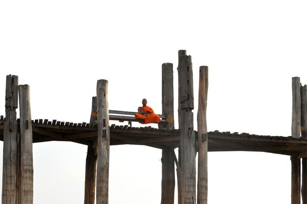 Монах, сидящий на деревянном мосту Убэйн в Амарапуре, округ Мандалай, Мьянма - Sputnik Абхазия