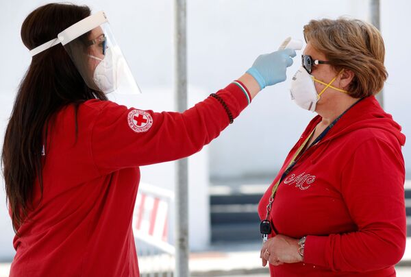 Волонтер Красного Креста проверяет температуру у посетительницы перед входом на рынок в Чистернино - Sputnik Абхазия