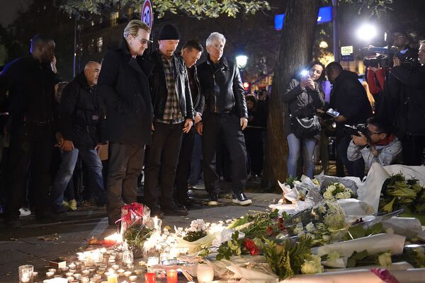 Irish band U2 (From L) lead singer Bono, guitarist The Edge, drummer Larry Mullen Jr and bass player Adam Clayton pay homage to attacks victims near the Bataclan concert hall on November 14, 2015 in Paris, a day after a series of coordinated attacks in and around Paris. Islamic State jihadists claimed a series of coordinated attacks by gunmen and suicide bombers in Paris that killed at least 129 people in scenes of carnage at a concert hall, restaurants and the national stadium. U2 has canceled two sold-out concerts in Paris, including one to be broadcast live on November 14, and Foo Fighters cut short their tour after attacks that killed at least129 people.  AFP PHOTO / FRANCK FIFE (Photo by FRANCK FIFE / AFP) - Sputnik Абхазия