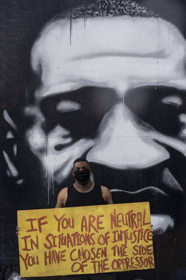 Мужчина с плакатом на месте убийства афроамериканца Джорджа Флойда в Миннеаполисе штат Миннесота - Sputnik Абхазия