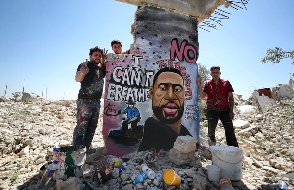 Сирийские художники Азиз Асмар и Анис Хамдун на фоне граффити с изображением убитого полицейским афроамериканца Джорджа Флойда в Идлибе, Сирия - Sputnik Абхазия