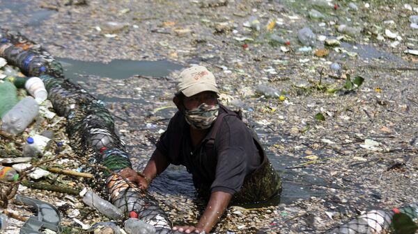 Сбор мусора, смытого дождями и удерживаемого барьером, установленным в одном из притоков озера в Аматитлане, Гватемала - Sputnik Аҧсны