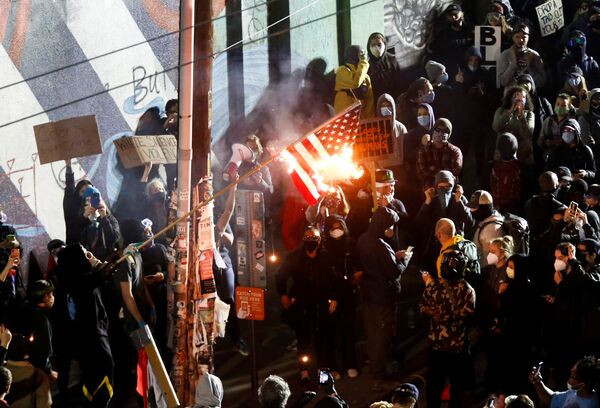 Протестующие сжигают американский флаг во время акции протеста против расового неравенства в Сиэтле - Sputnik Абхазия
