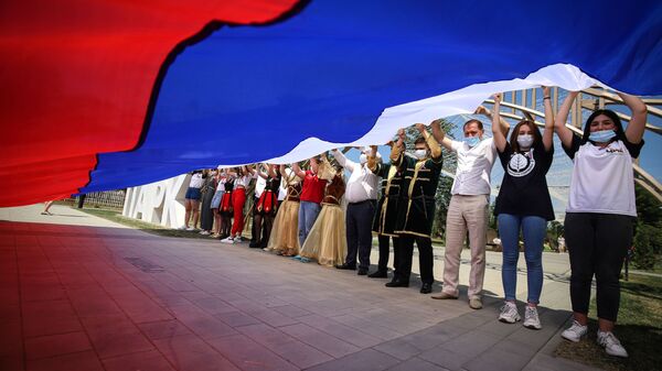 Участники празднований Дня России держат российский флаг в парке Дружбы города Георгиевска Ставропольского края - Sputnik Абхазия