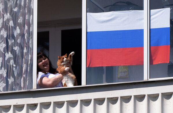 Жительница Красноярска смотрит выступление музыкального ансамбля в День России из окна своей квартиры - Sputnik Абхазия