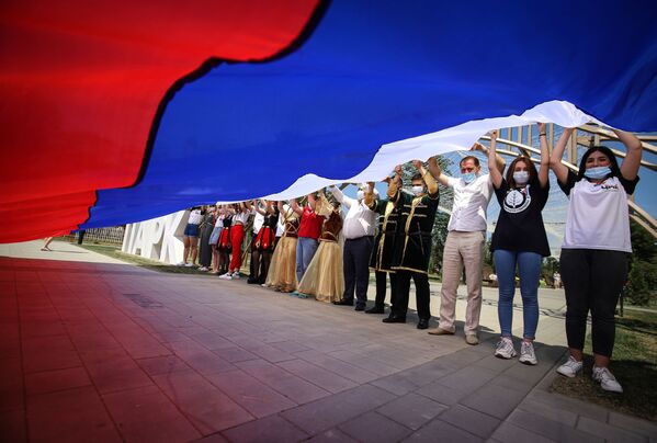 Участники празднований Дня России держат российский флаг в парке Дружбы города Георгиевска Ставропольского края - Sputnik Абхазия