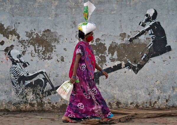 Женщина в защитной маске проходит мимо граффити в Мумбаи, Индия - Sputnik Абхазия