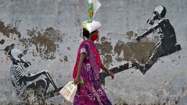 Женщина в защитной маске проходит мимо граффити в Мумбаи, Индия - Sputnik Абхазия
