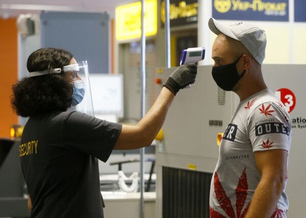 Пассажир в защитной маске проходит температурный контроль в международном аэропорту Борисполь в Киеве - Sputnik Абхазия