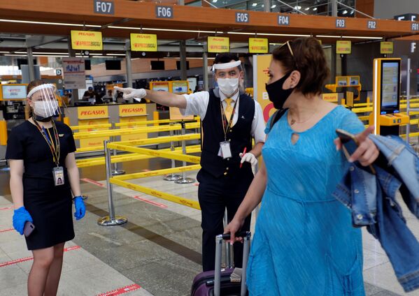 Сотрудники авиакомпании Pegasus Airlines в защитных масках и экранах указывают пассажиру нужное направление в международном аэропорту имени Сабихи Гекчен в Стамбуле - Sputnik Абхазия
